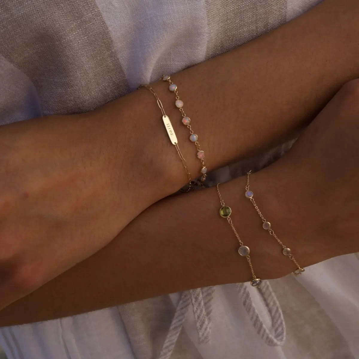 Layered 1 Petite Nameplate, Newport Opal, Bayberry 7 Moonstone, and Grand Birthstone Bracelets shown stacked on wrist in 14k gold.