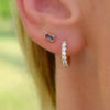 Close-up of woman's ear wearing a Providence Alexandrite stud earring and a Rosecliff Diamond earring in 14k yellow gold.