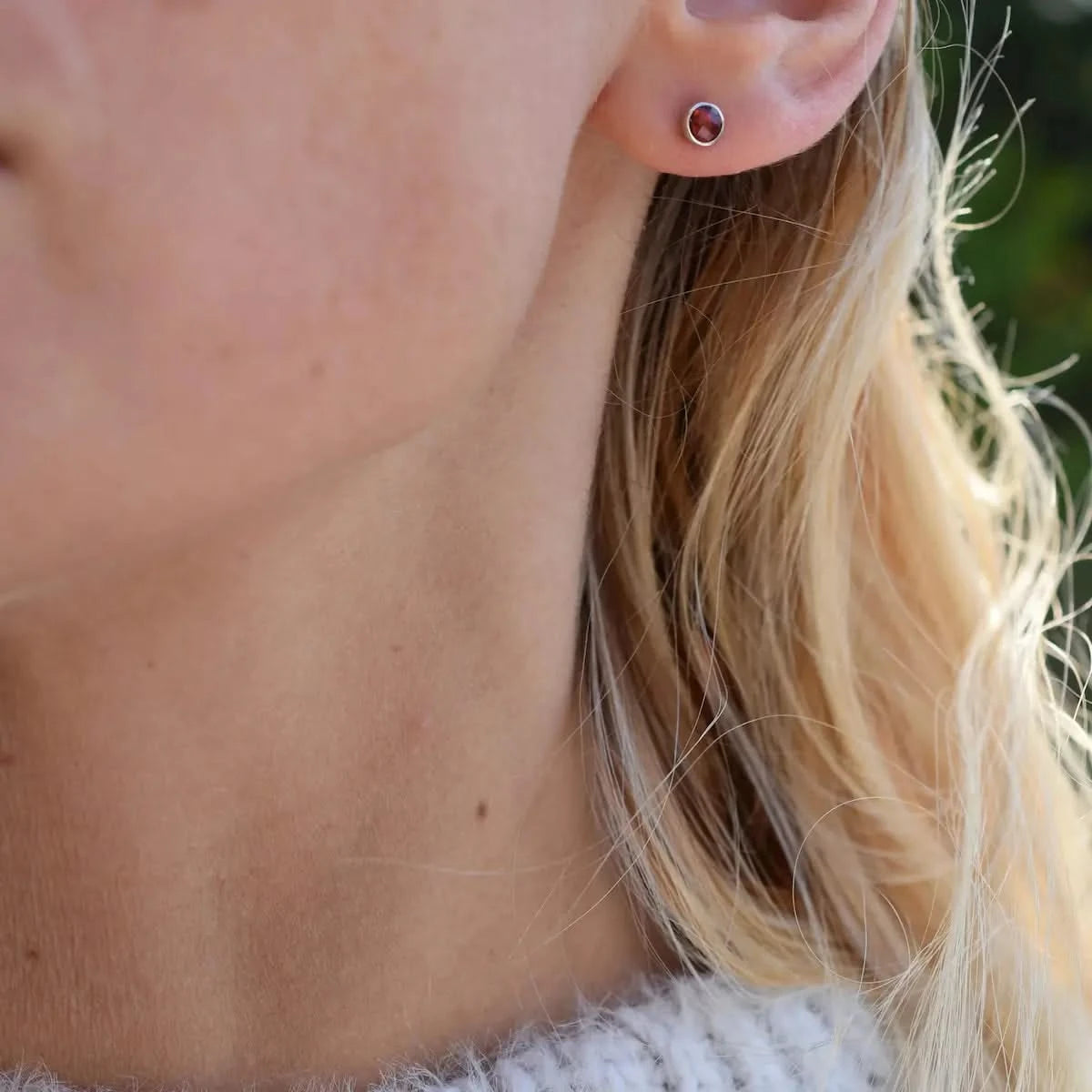 Woman wearing a Birthstone Stud Earring featuring a 4 mm briolette cut Garnet bezel set in 14k white gold