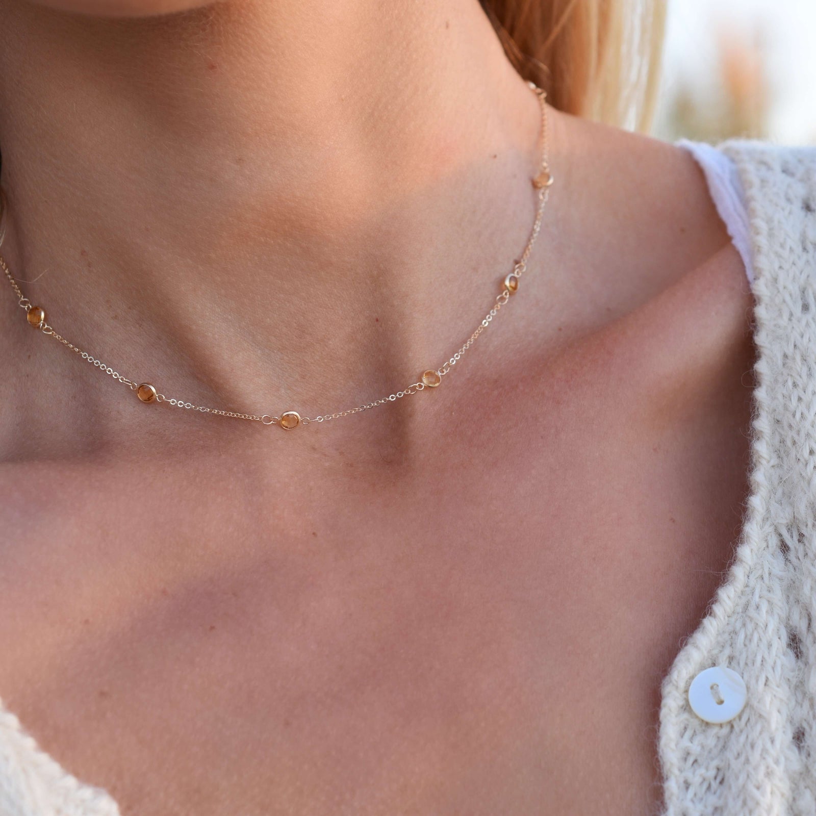 Woman wearing a Bayberry 11 Birthstone necklace featuring 4 mm briolette citrines bezel set in 14k gold