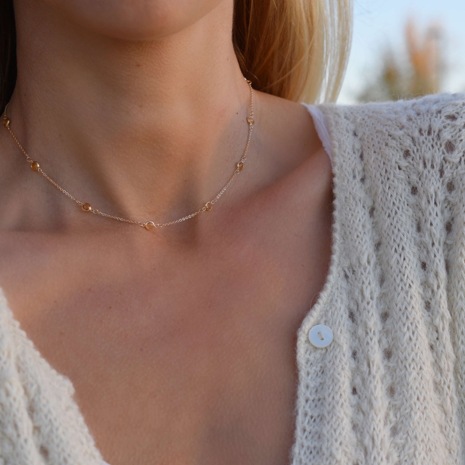 Woman wearing a Bayberry 11 Birthstone necklace featuring 4 mm briolette citrines bezel set in 14k yellow gold