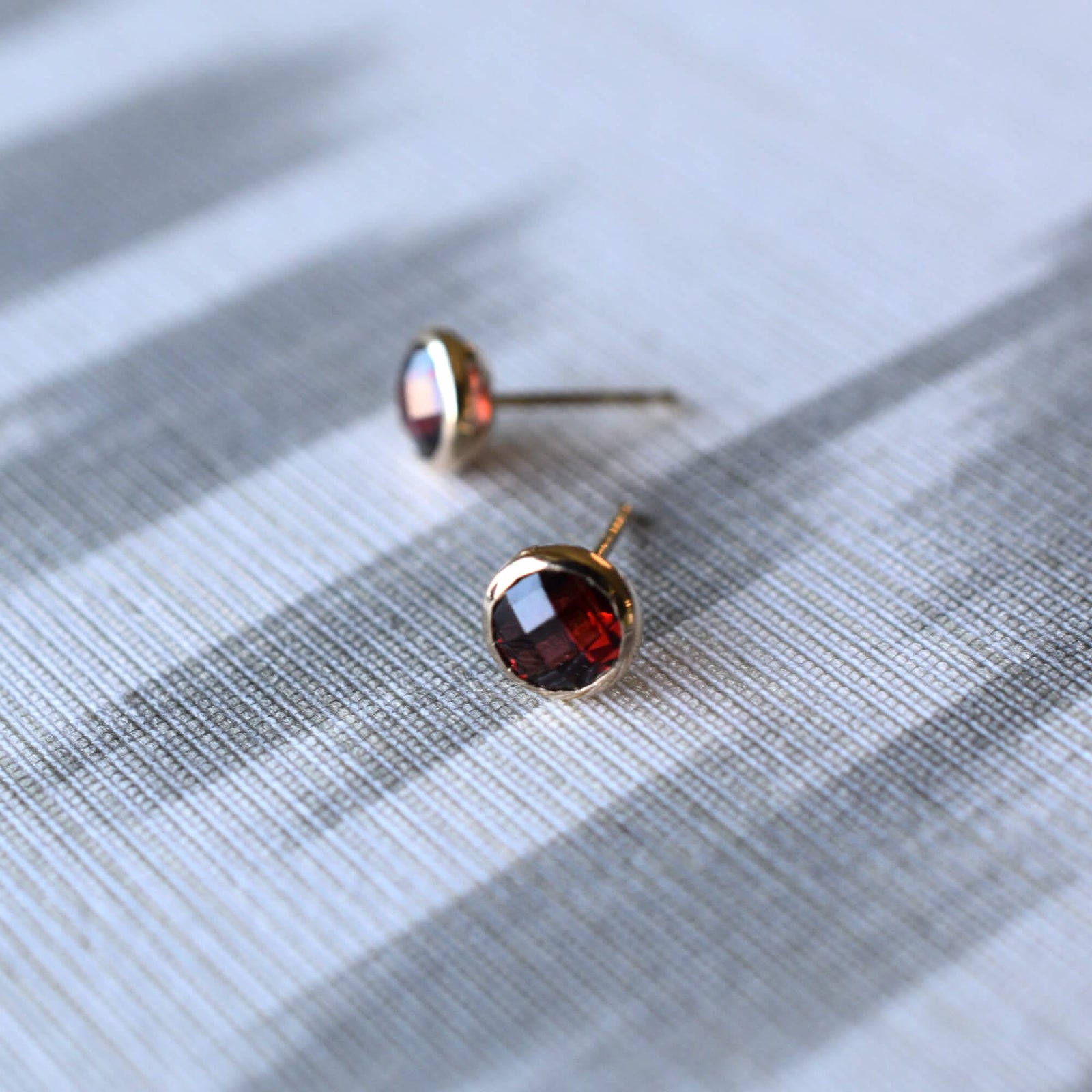 Pair of 14k yellow gold Grand stud earrings each featuring one 6 mm briolette cut bezel set garnet