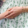 Woman holding her childs hand on her pregnant stomach while wearing Rosecliff rings, a Warren ring, & personalized bracelets.