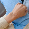 Wrist wearing a personalized Leo & Birthstone bracelet on a 5.2mm x 2mm paperclip chain featuring one 4mm bezel set gemstone.