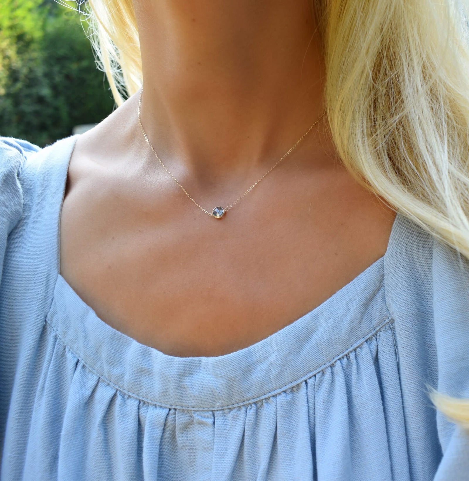 Woman wearing a Grand 14k yellow gold 1.17 mm cable chain necklace featuring one 6 mm briolette cut bezel set aquamarine