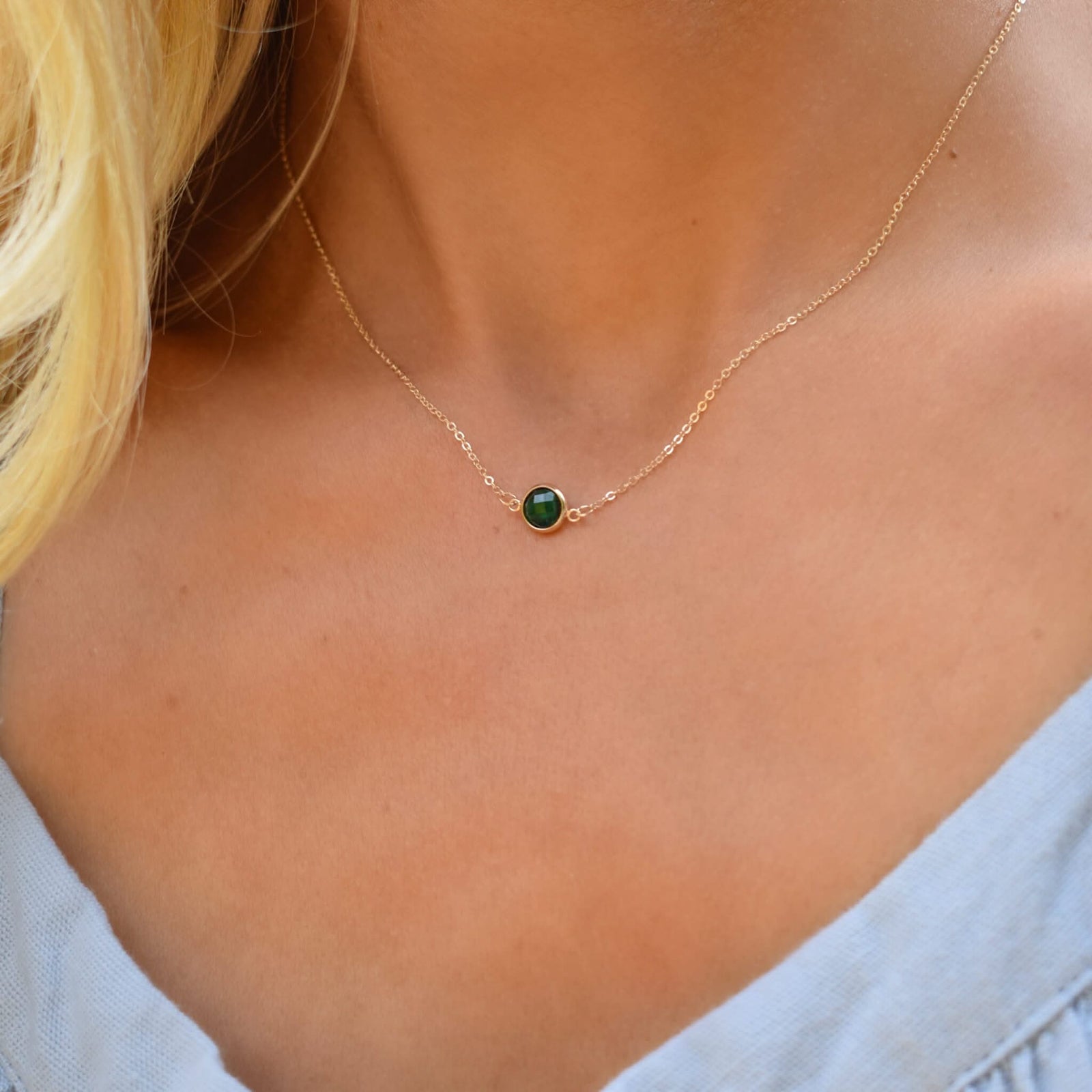 Woman wearing a Grand 14k yellow gold 1.17 mm cable chain necklace featuring one 6 mm briolette cut bezel set emerald