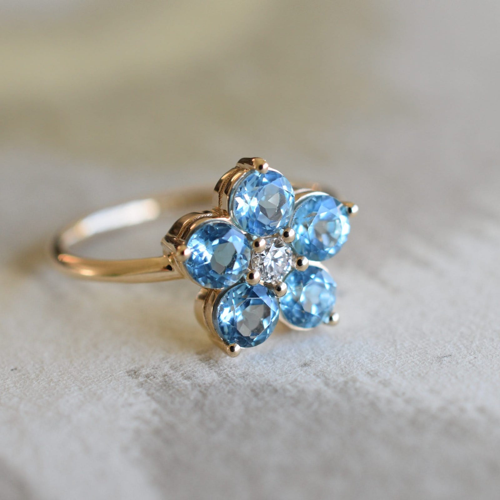 A Greenwich ring featuring five 4 mm faceted round cut nontucket blue topaz and one 2.1 mm diamond prong set in 14k gold