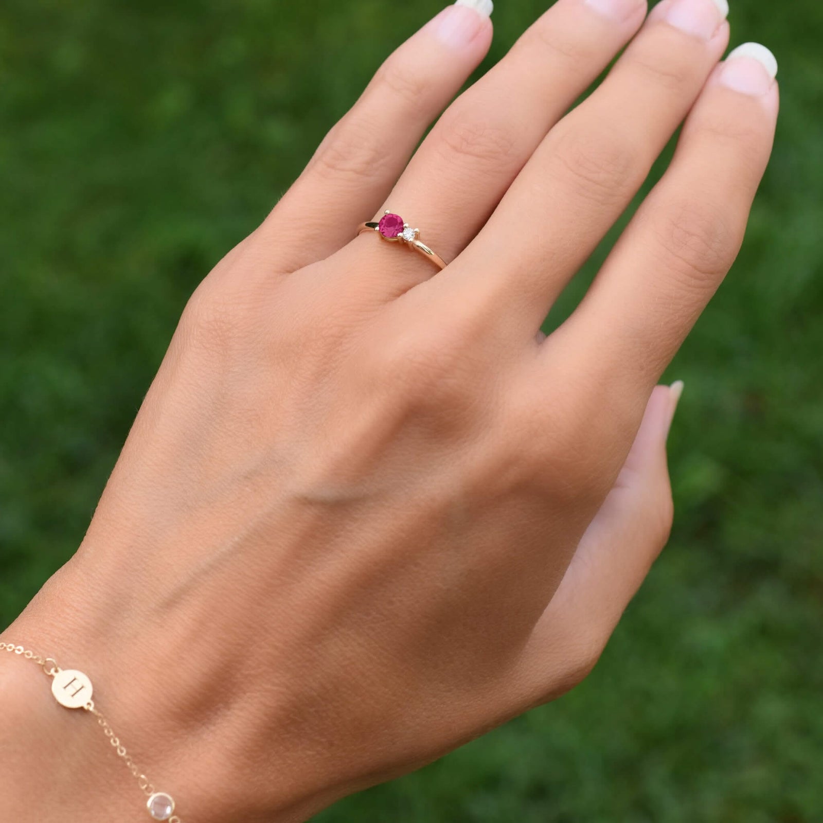 Woman with a Greenwich ring featuring one 4 mm faceted round cut ruby and one 2.1 mm diamond prong set in 14k yellow gold