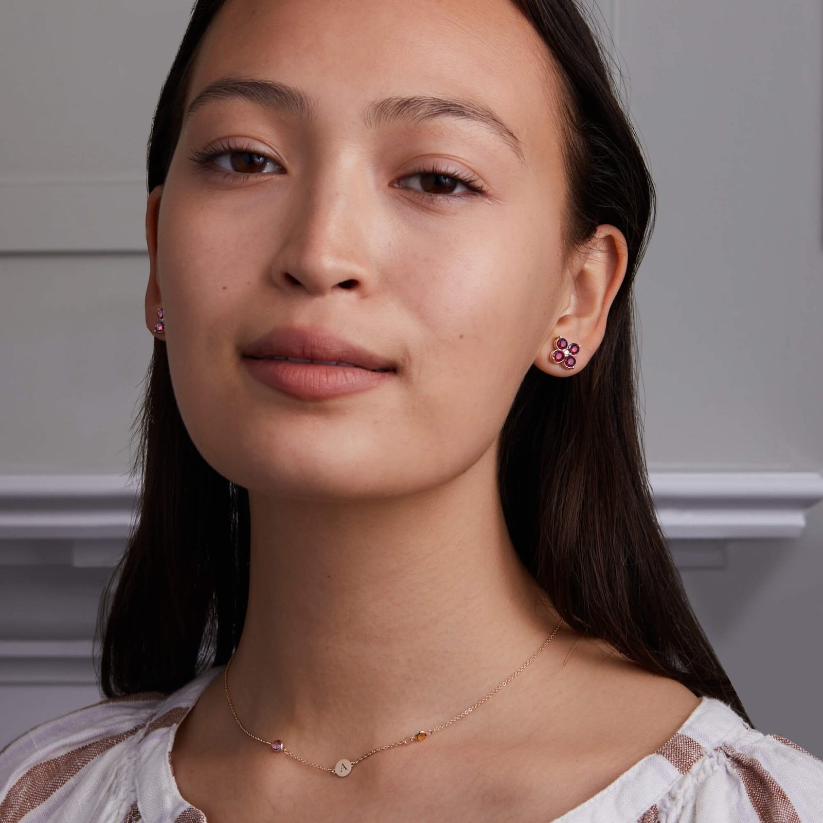 Woman adorned with Greenwich Birthstone Earrings in 14k Gold featuring four 4 mm faceted round cut, prong set Rubies and one 2.1 mm Diamond.