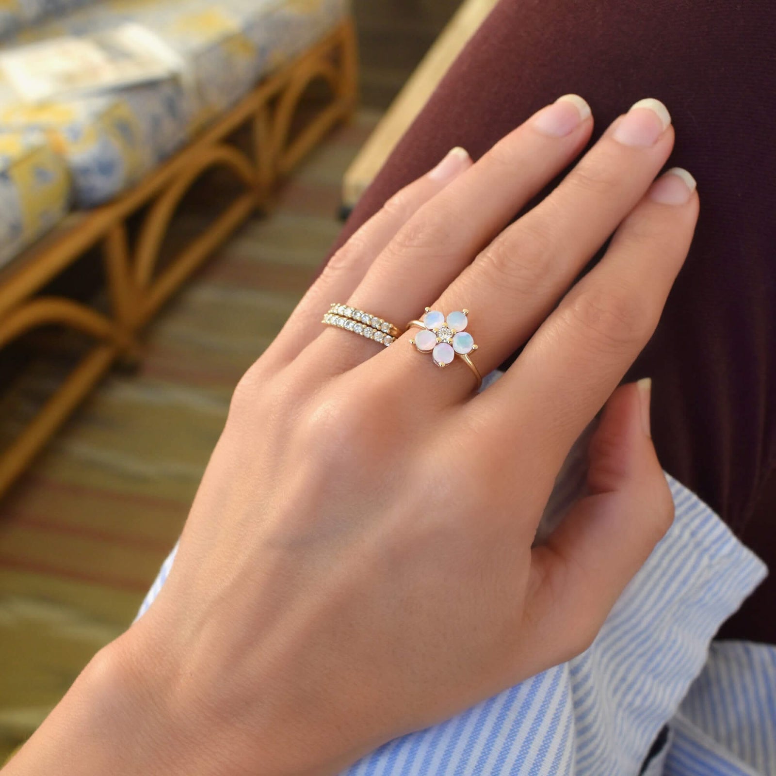 Woman wearing three rings including a Greenwich ring featuring five 4 mm faceted round cut opals and one 2.1 mm diamond prong set in 14k gold