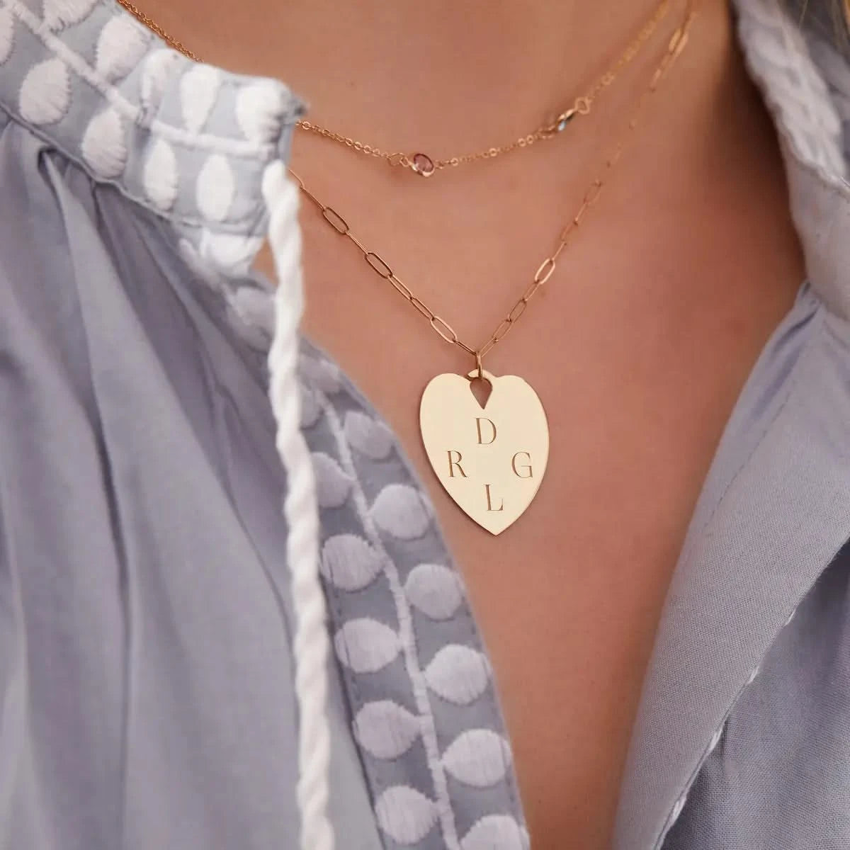 Personalized Engravable Heart Pendant with four initials styled on neckline, paired with fine gold chains.