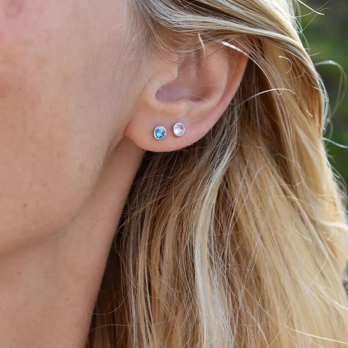 Woman wearing Stud Earrings featuring 4 mm briolette cut White Topaz and Blue Topaz bezel set in 14k yellow gold