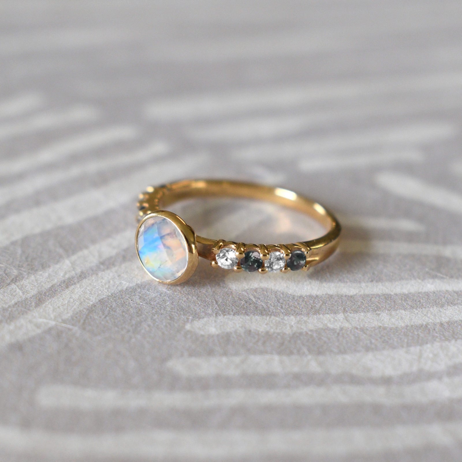 14k gold Rosecliff Grand Ring with a 6 mm briolette-cut Moonstone and eight alternating 2 mm round-cut Diamonds and Moonstonees