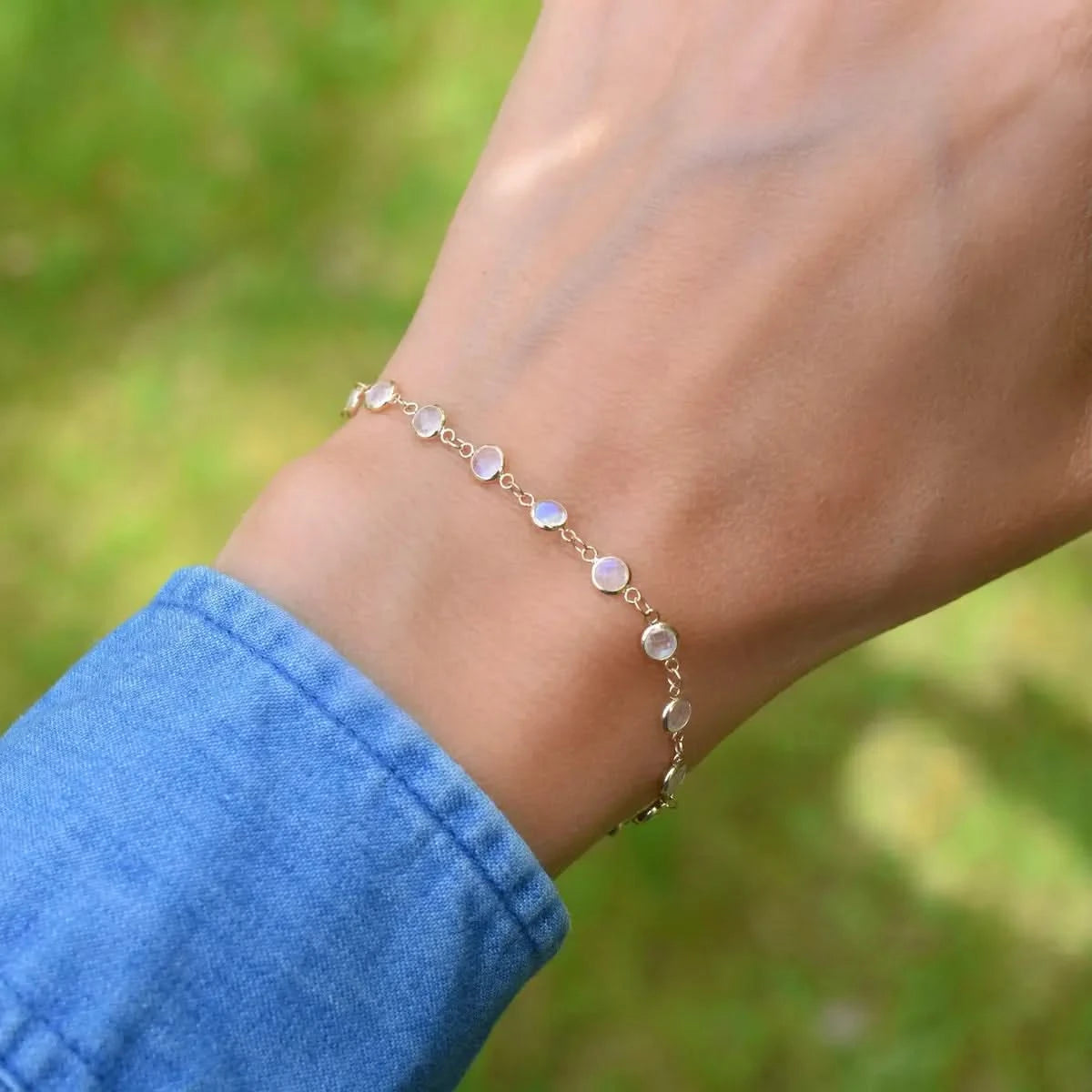 Woman wearing a Newport 14k yellow gold bracelet featuring 4 mm briolette cut bezel set moonstones