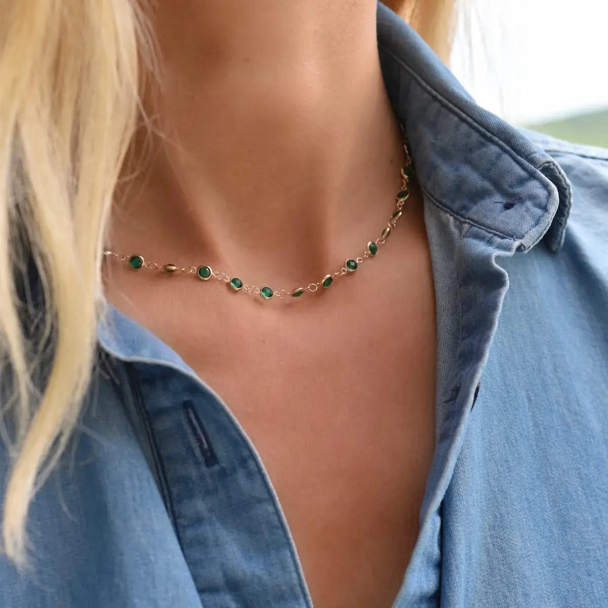 Woman with a Newport necklace featuring 4 mm briolette cut emeralds bezel set in 14k yellow gold