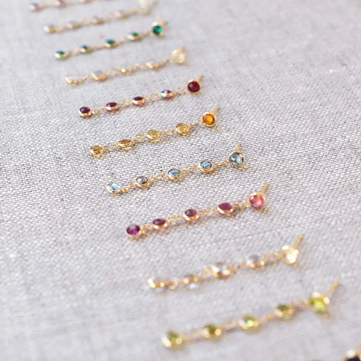 Nine Newport earrings each featuring five 4 mm briolette cut gemstones in various colors bezel set in 14k yellow gold