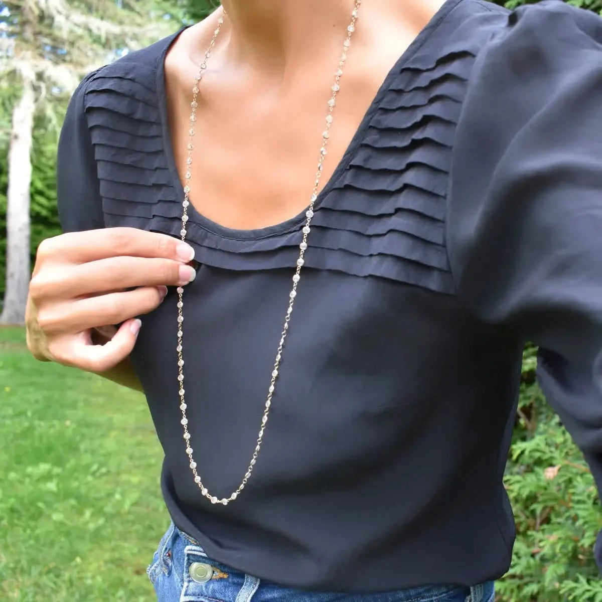 Woman wearing a Newport Wrap necklace featuring 4 mm briolette cut moonstones bezel set in 14k yellow gold