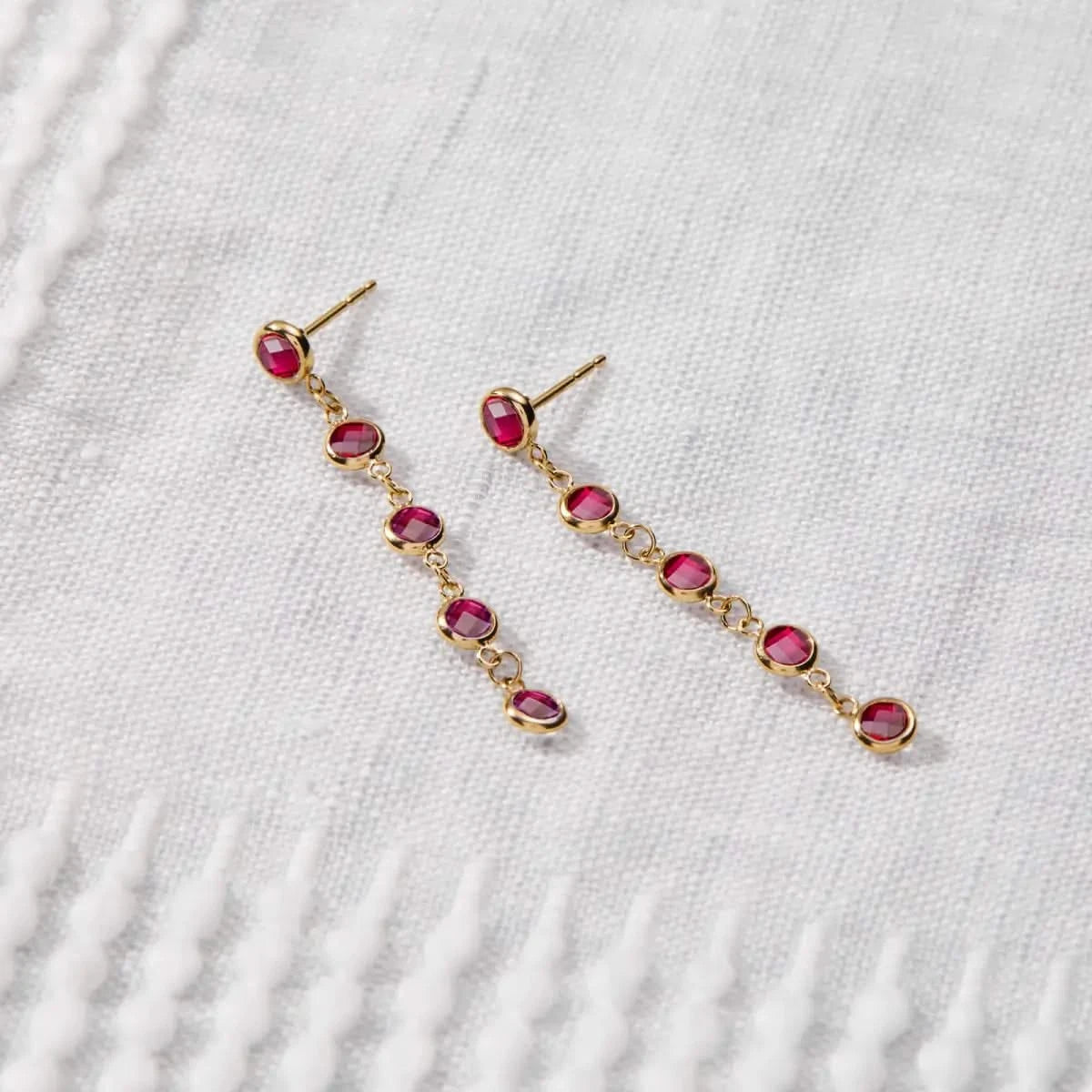 Newport Ruby Earrings in 14k gold are laid flat to highlight the five bezel-set July birthstones in a linear drop style.