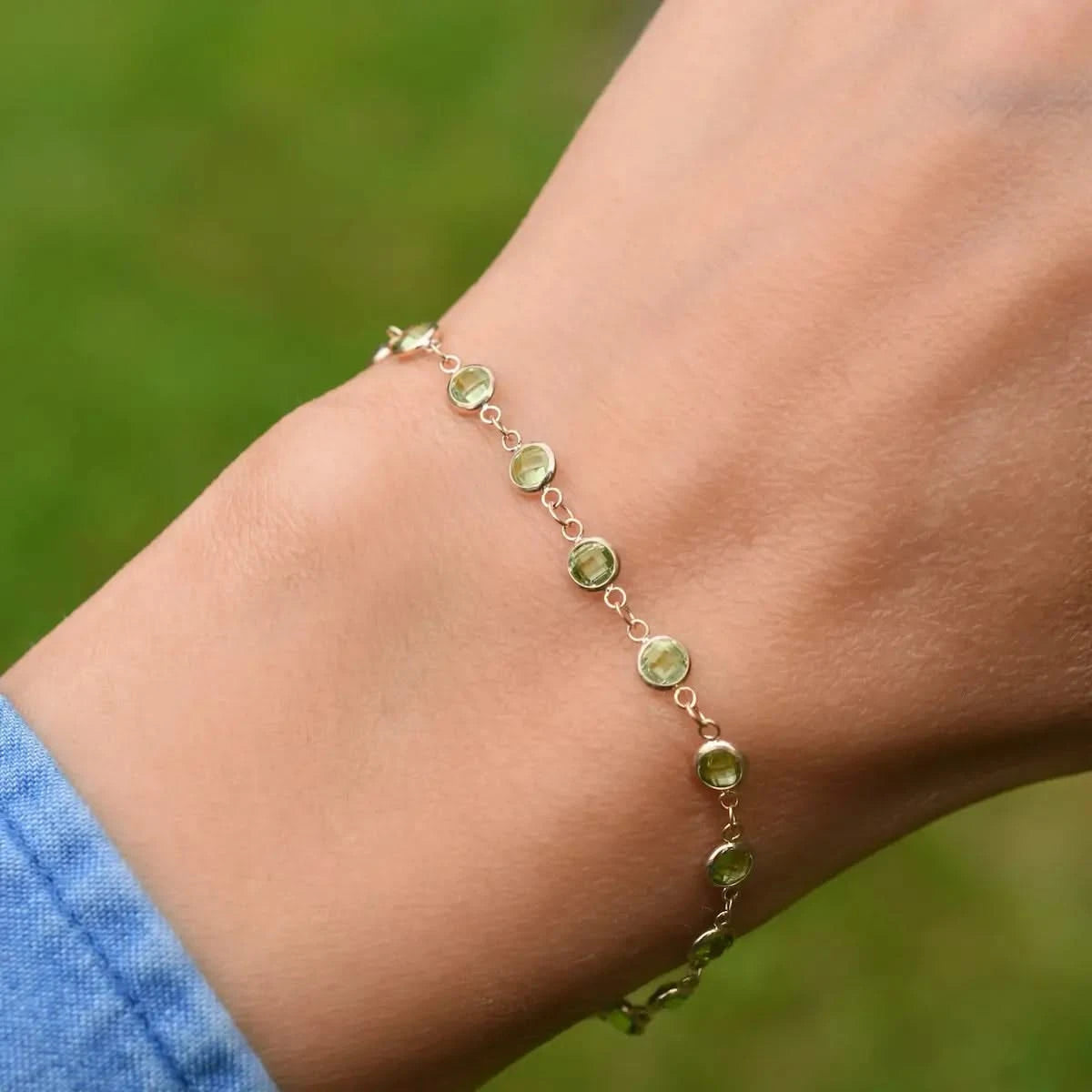 Woman wearing a Newport 14k yellow gold bracelet featuring 4 mm briolette cut bezel set peridots