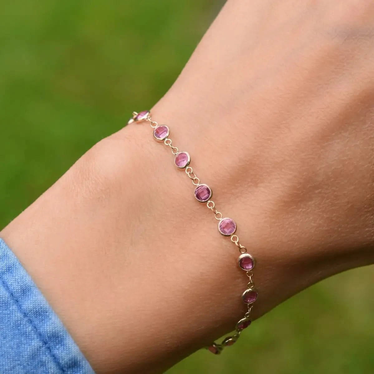 Woman wearing a Newport 14k yellow gold bracelet featuring 4 mm briolette cut bezel set pink sapphires
