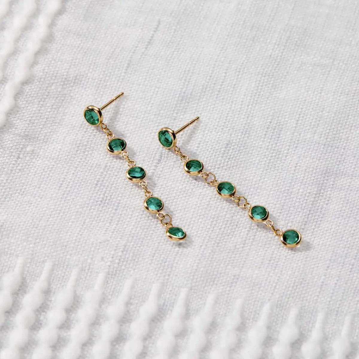 Newport Emerald Earrings in 14k gold were displayed with five bezel-set emeralds arranged in a linear drop style.
