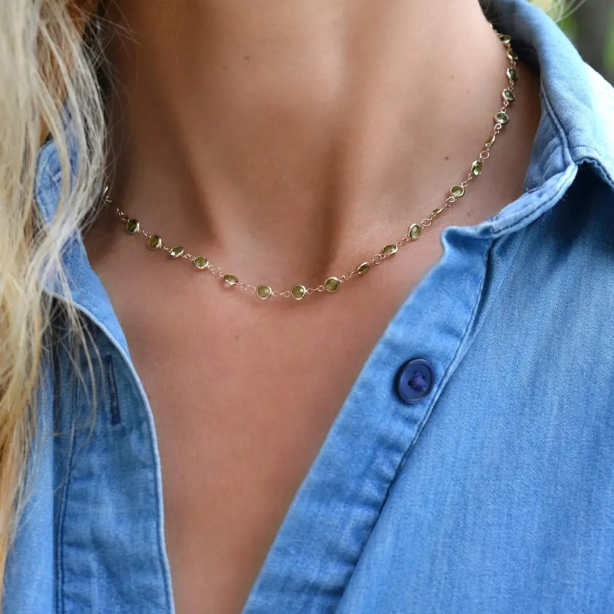 Woman with a Newport necklace featuring 4 mm briolette cut peridots bezel set in 14k yellow gold