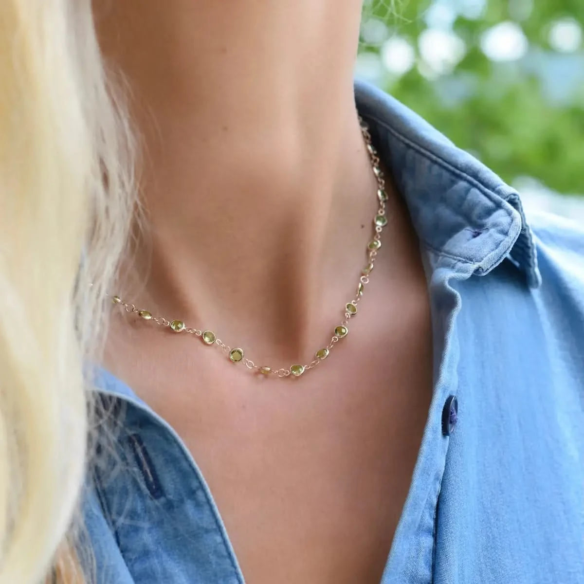 Woman wearing a Newport necklace featuring 4 mm briolette cut peridots bezel set in 14k yellow gold