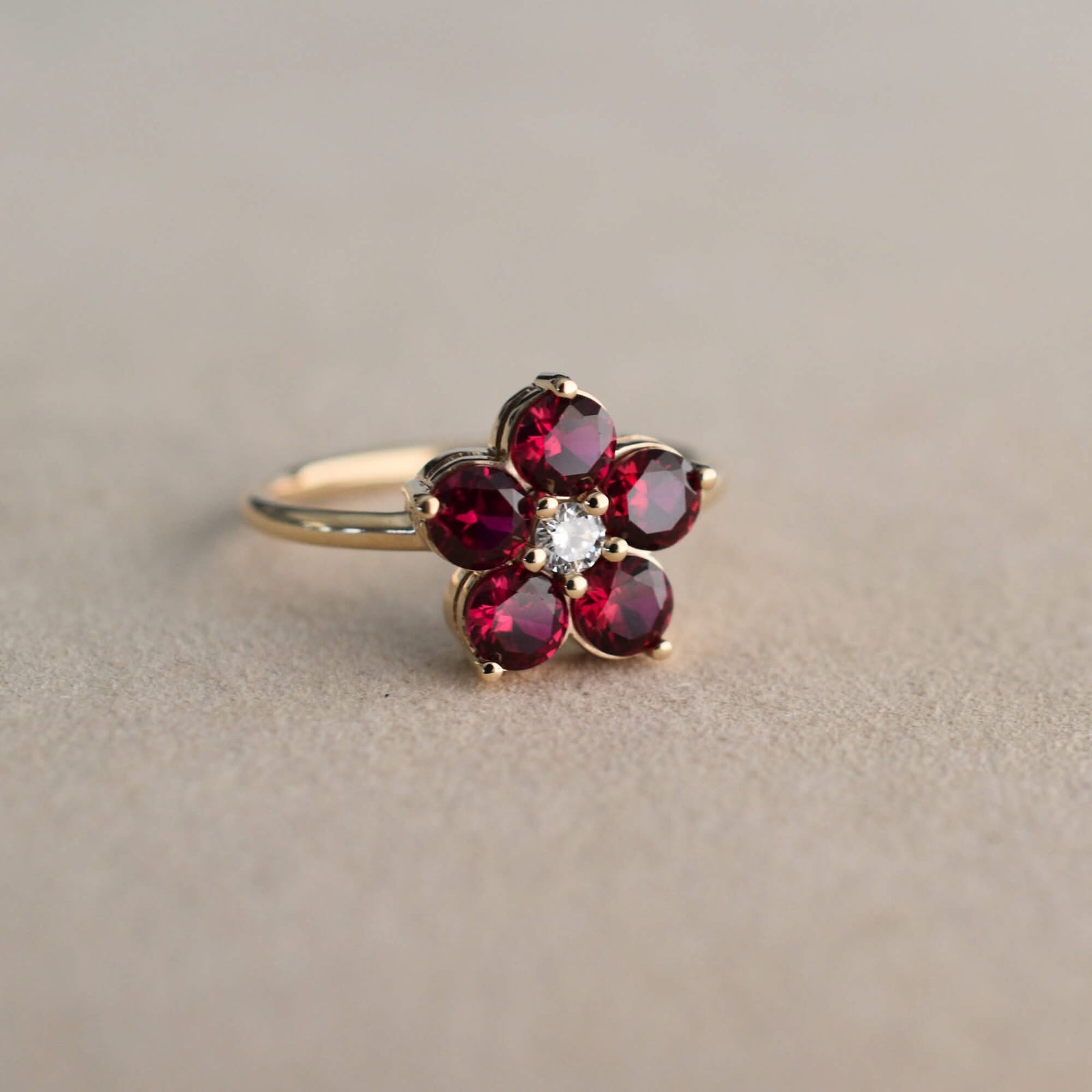 A Greenwich ring featuring five 4 mm faceted round cut garnet and one 2.1 mm diamond prong set in 14k gold