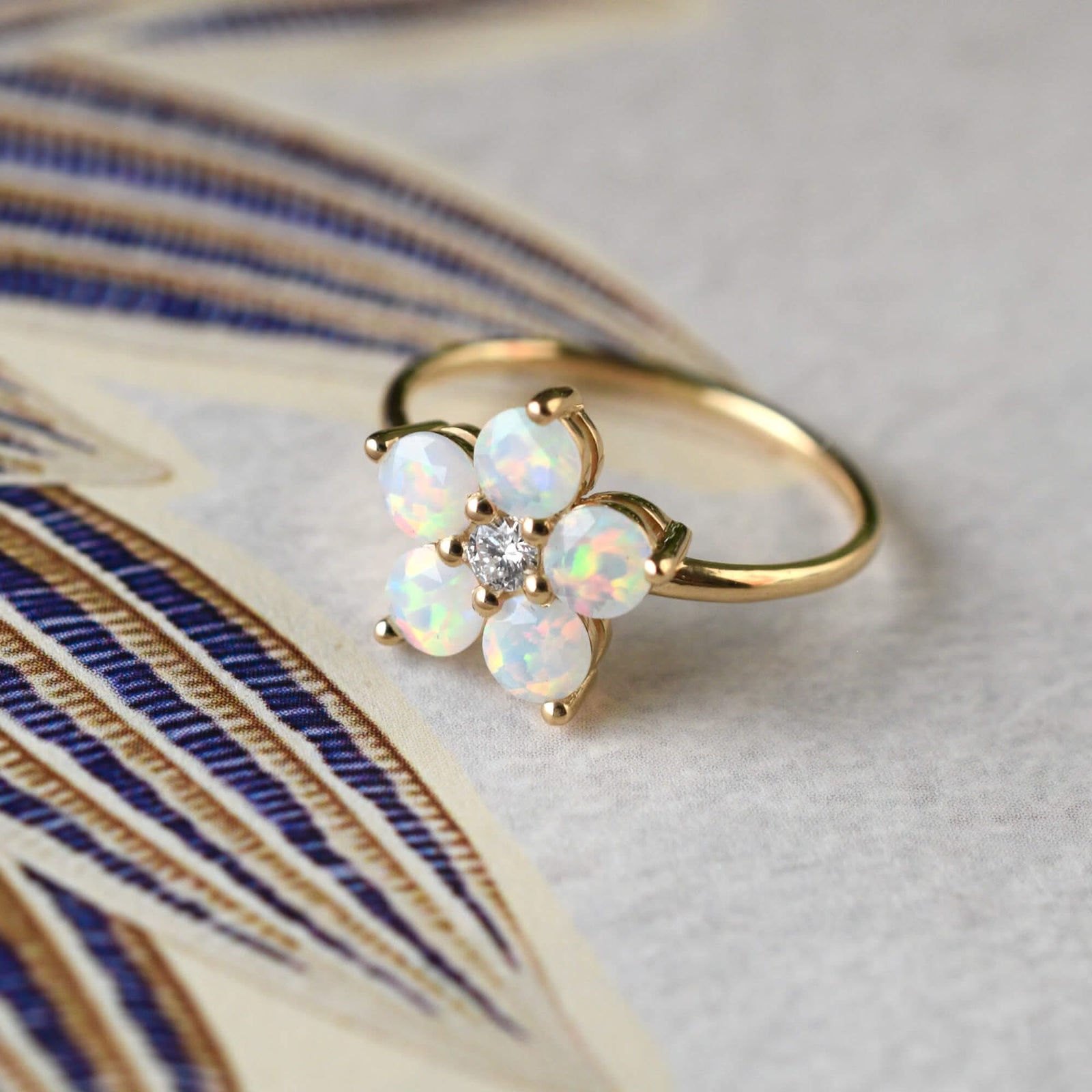 A Greenwich ring featuring five 4 mm faceted round cut opal and one 2.1 mm diamond prong set in 14k gold