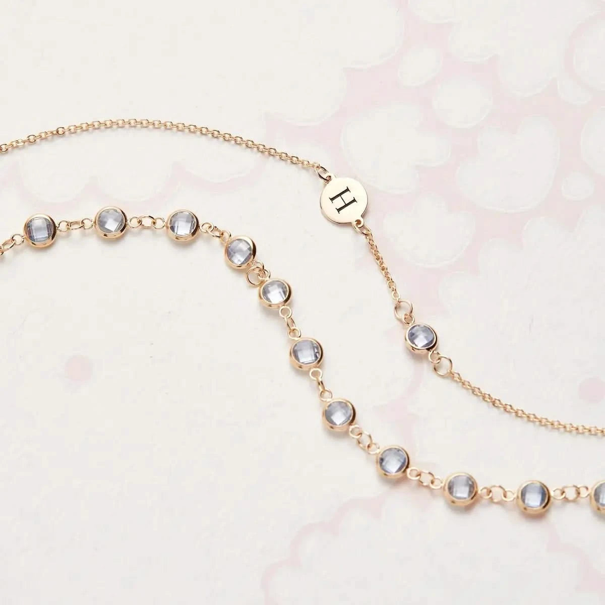 Flatlay of Newport Aquamarine necklace in 14k gold with personalized initial charm.