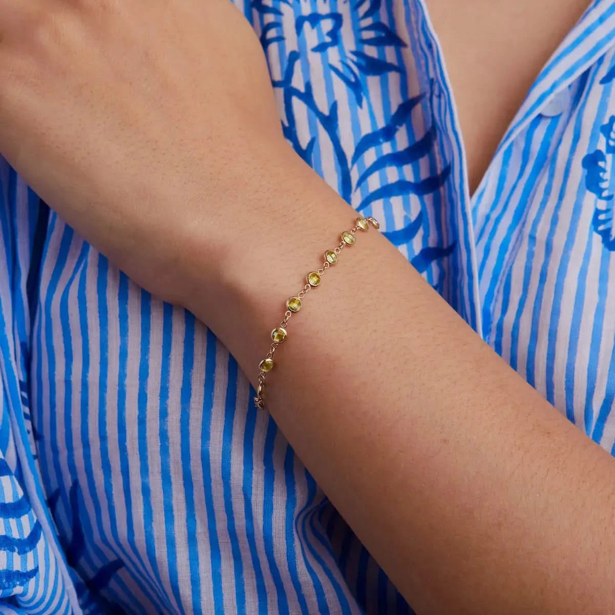 Close-up of the Newport Peridot Bracelet in 14k Gold worn on wrist, featuring round bezel set Peridot gemstones.