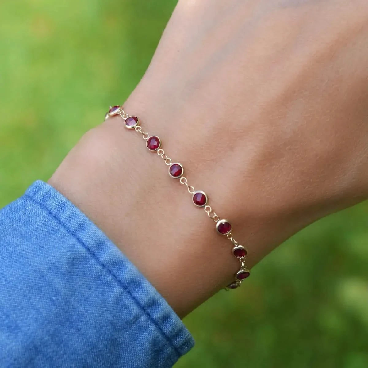 Woman wearing a Newport 14k yellow gold bracelet featuring 4 mm briolette cut bezel set rubies