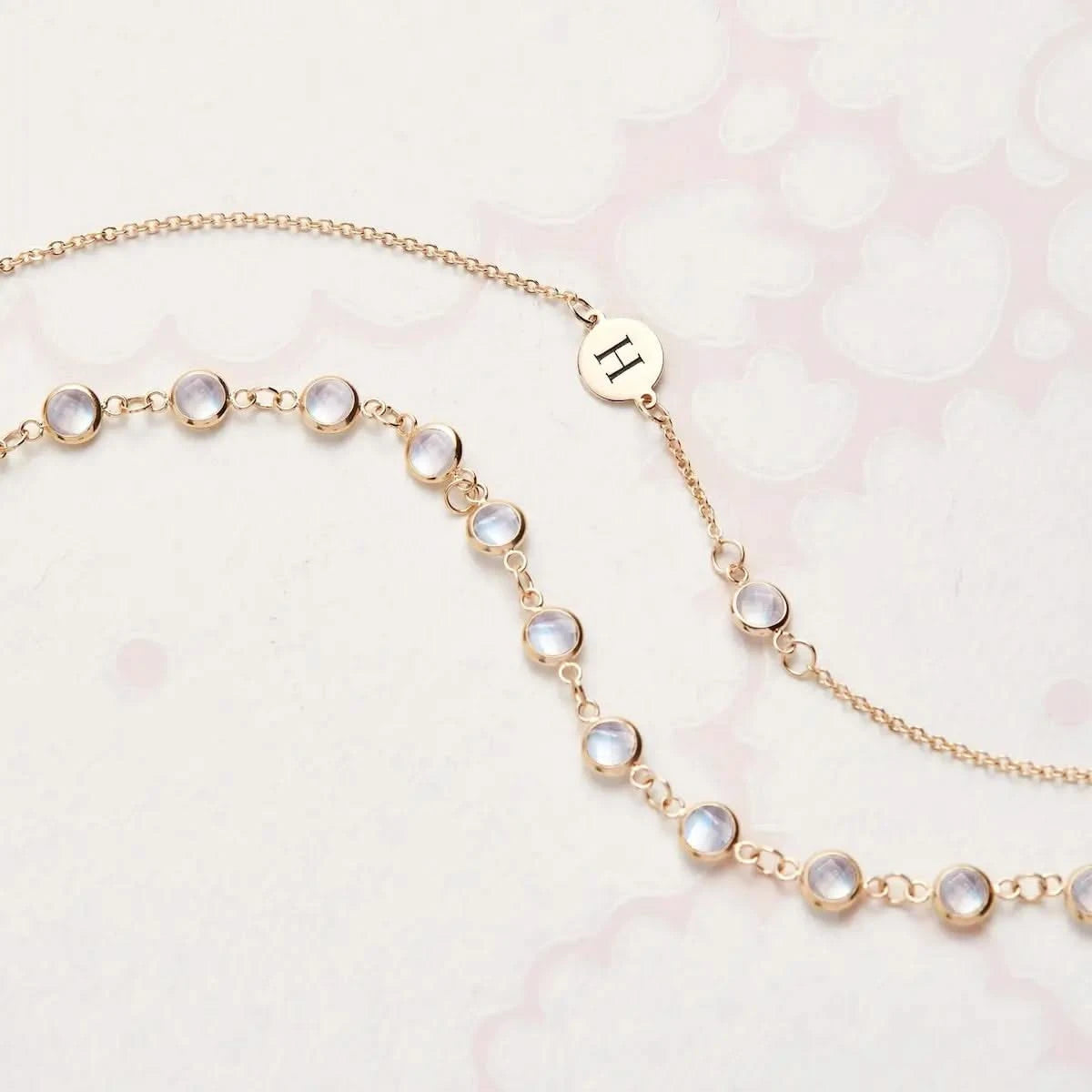 Close-up of Newport Moonstone Necklace in 14k gold featuring bezel-set round briolette cut stones and engraved initial charm