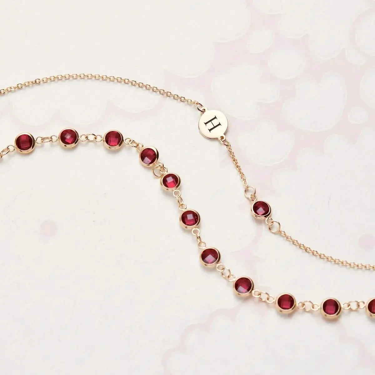 Flatlay of Newport Ruby Chain in 14k Gold, shown with engraved initial charm.