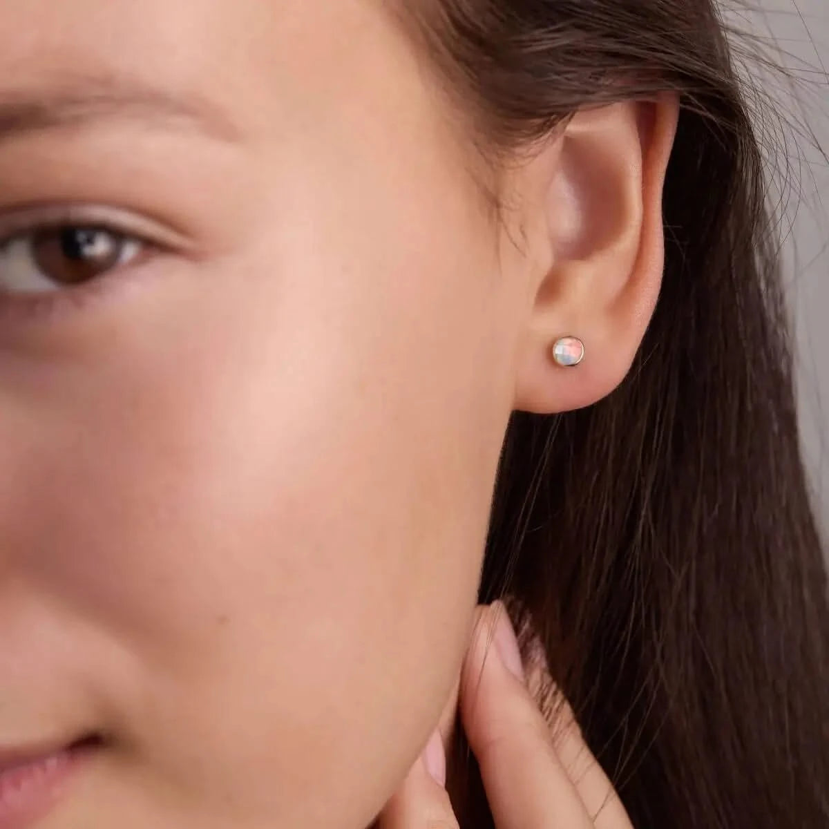 Woman wearing a Birthstone Stud Earring featuring a 4 mm briolette cut Opal bezel set in 14k yellow gold