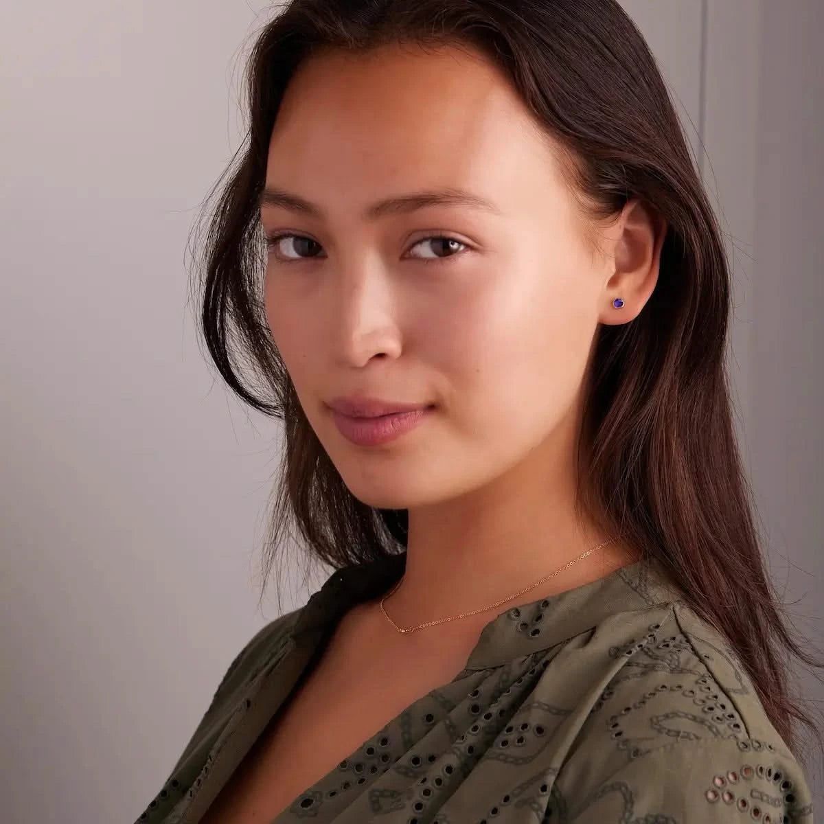 Woman wearing a 14k yellow gold Stud Earring featuring a 4 mm briolette cut Amethyst bezel set