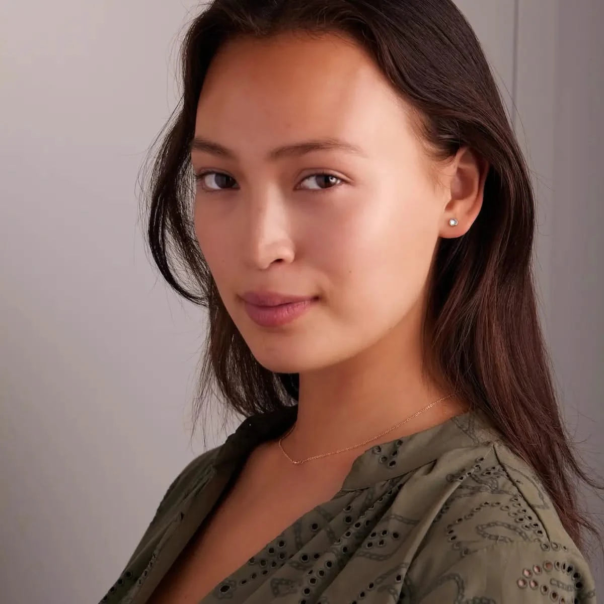 Woman wearing a Petite Birthstone Stud Earring featuring a 4 mm briolette cut Aquamarine bezel set in 14k yellow gold