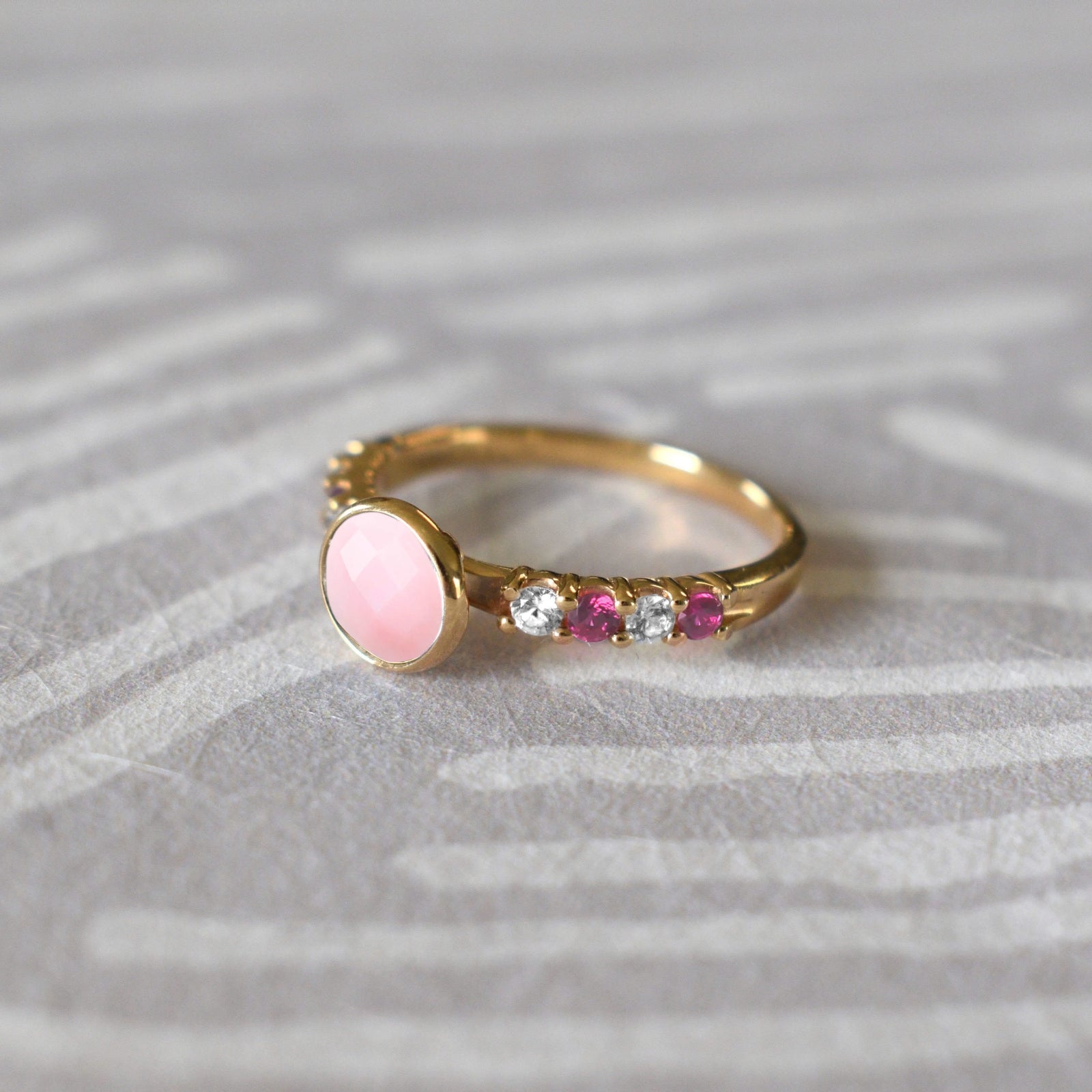 14k gold Rosecliff Grand Ring showcasing a 6 mm round, briolette-cut Opal and eight alternating 2 mm round-cut Diamonds and Pink Sapphires.