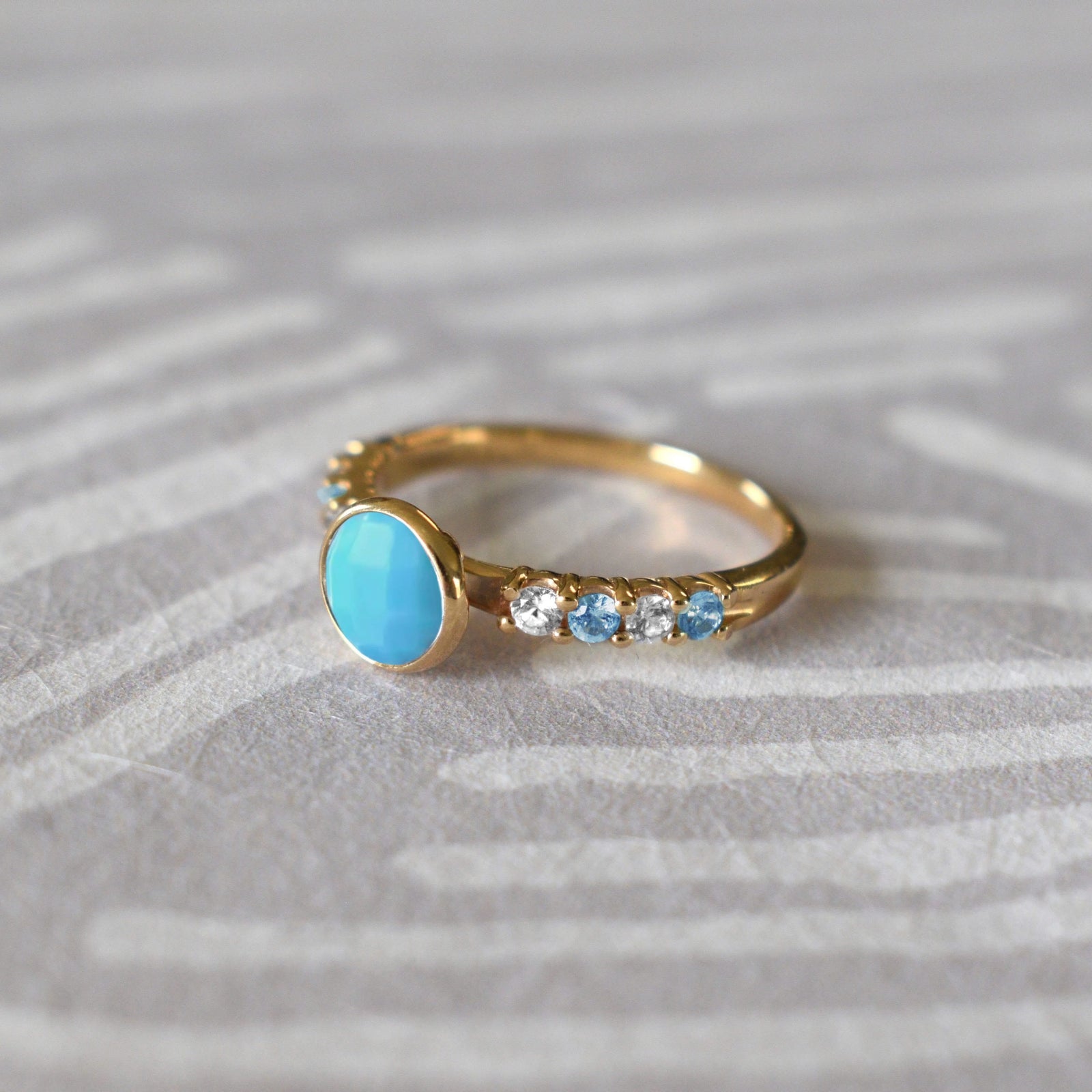 14k gold Rosecliff Grand Ring showcasing a 6 mm round, briolette-cut Turquoise and eight alternating 2 mm round-cut Blue Topazes and Diamonds.