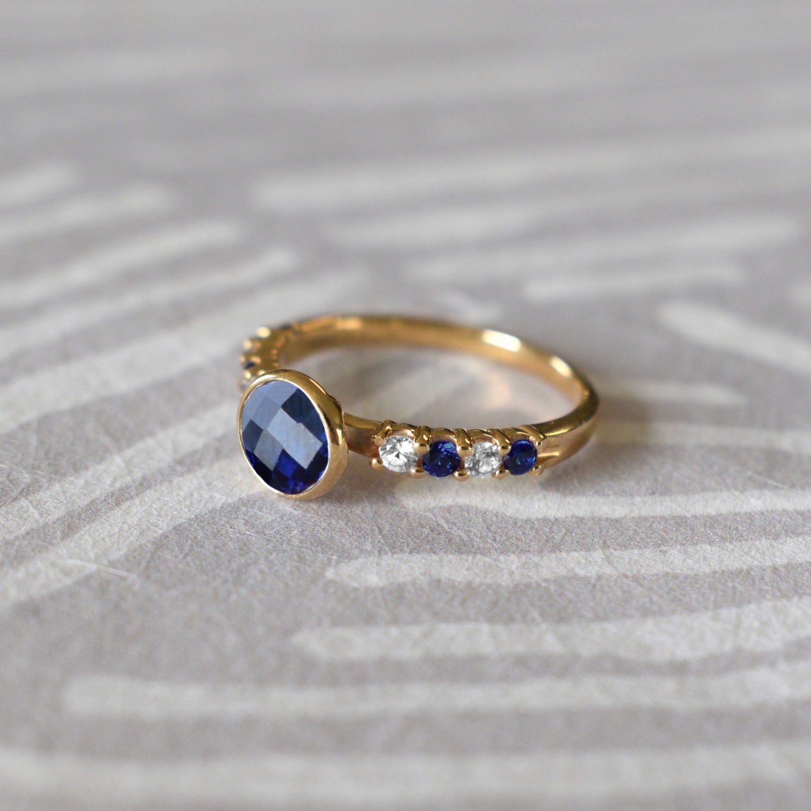 14k gold Rosecliff Grand Ring with a 6 mm briolette-cut Sapphire and eight alternating 2 mm round-cut Diamonds and Sapphires.