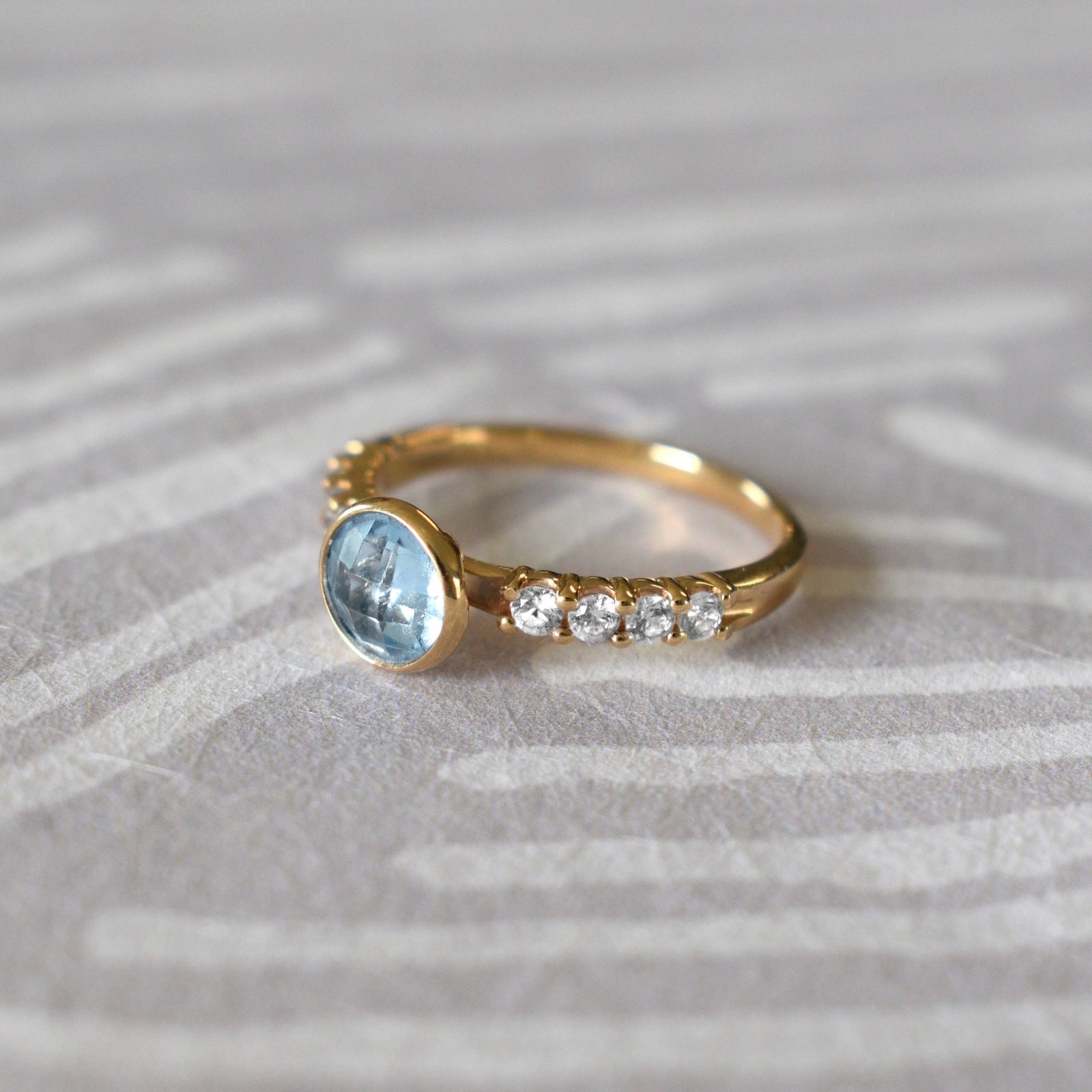 14k yellow gold Rosecliff Grand Ring with a 6 mm round, briolette-cut Blue Topaz and eight 2 mm round-cut Diamonds.