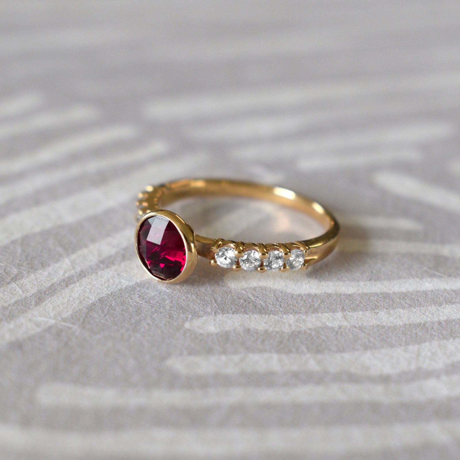 Rosecliff Grand Ring in a 14k gold, featuring a 6 mm round, briolette-cut Ruby and eight 2 mm round-cut Diamonds.