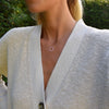 Woman wearing a Rosecliff open circle necklace with sixteen alternating pink sapphires & diamonds prong set in 14k gold