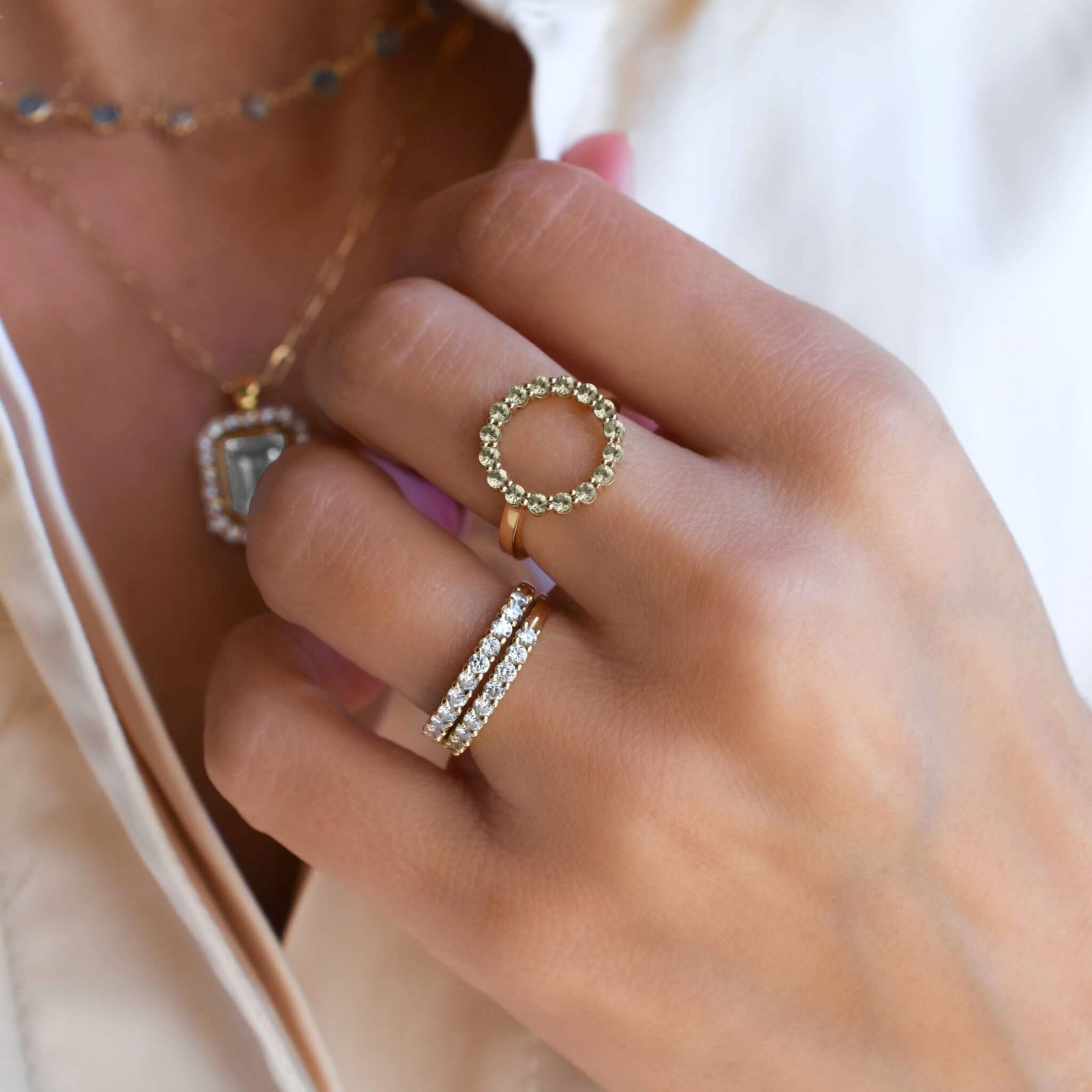 Woman wearing assorted jewelry including a Rosecliff open circle ring featuring sixteen 2 mm peridots prong set in 14k gold