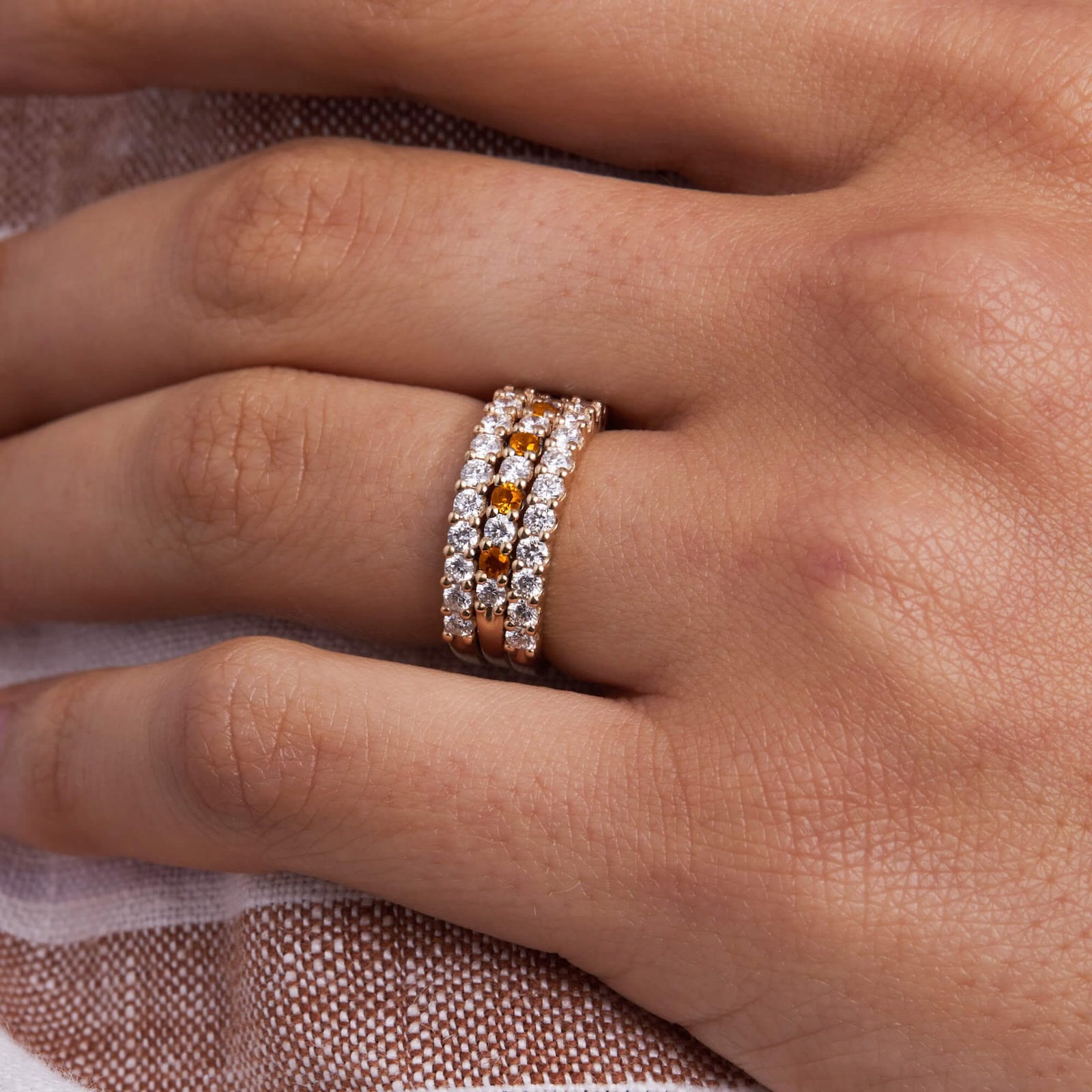 Hand wearing a Rosecliff stackable ring featuring eleven alternating 2mm citrines and diamonds prong set in 14k yellow gold