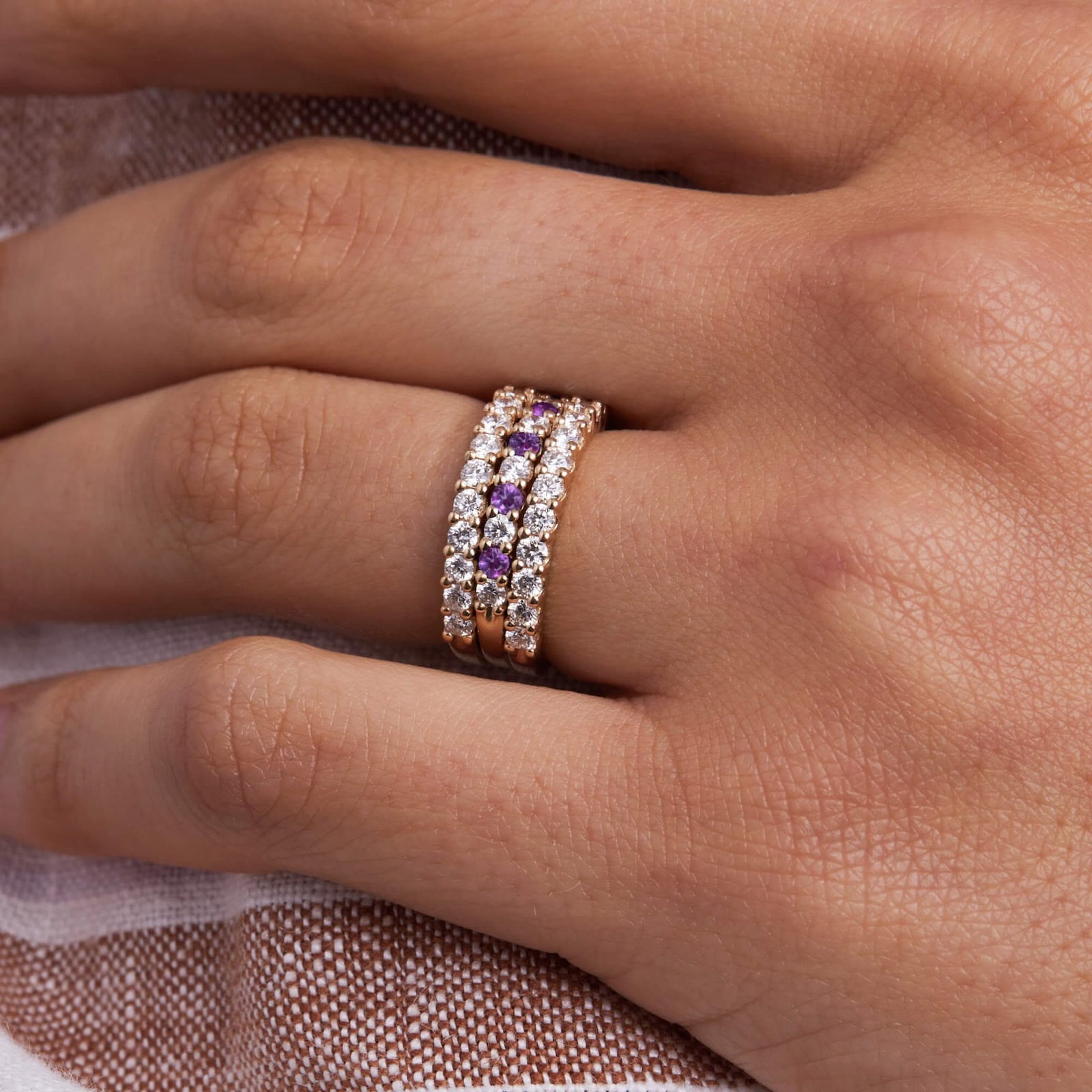 Woman adorned with a Rosecliff stackable rings, including a Rosecliff stackable ring featuring eleven alternating 2mm amethysts and diamonds prong set in 14k yellow gold.