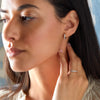 Woman wearing a Rosecliff huggie earring in 14k yellow gold featuring nine 2mm faceted round cut prong set aquamarines