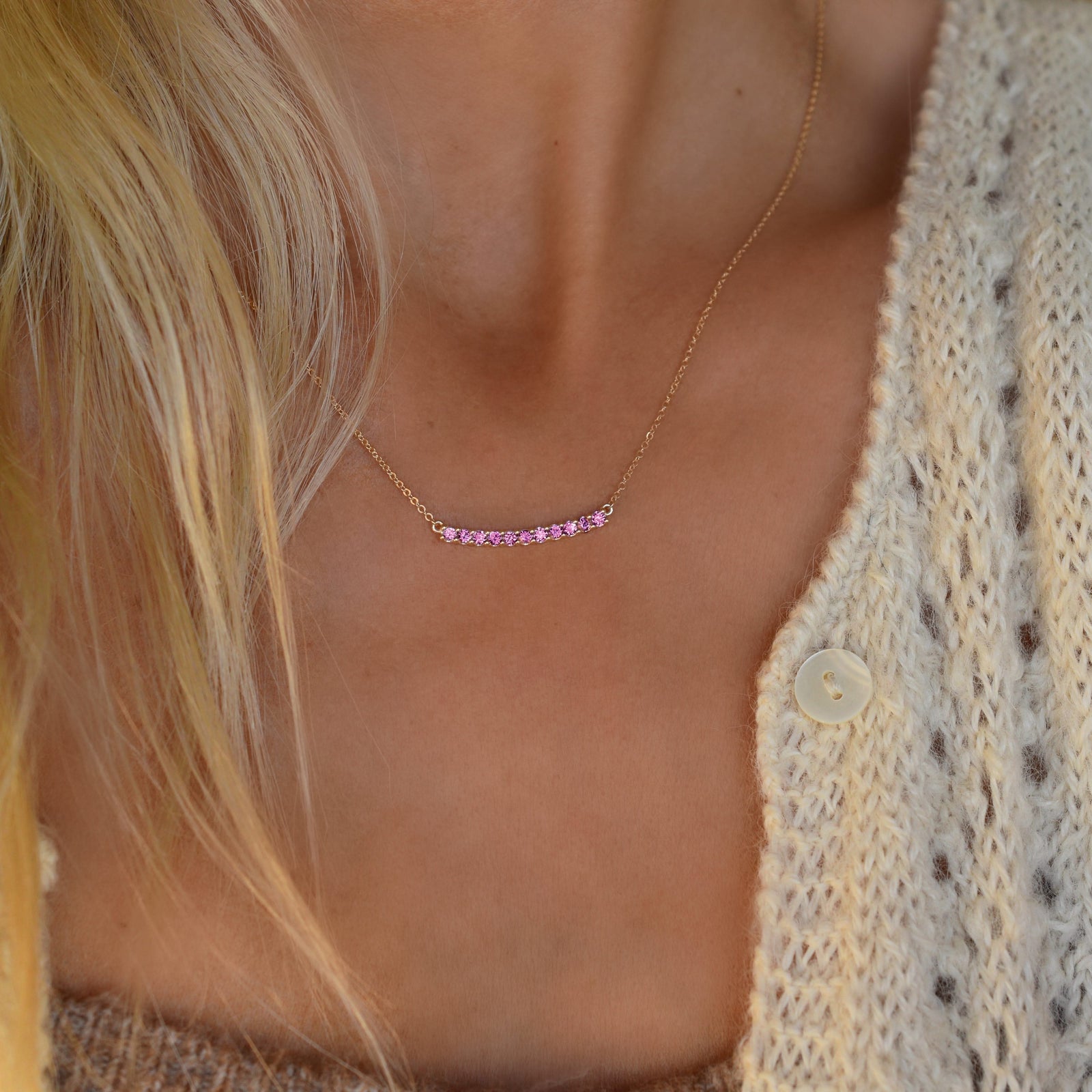Woman with a Rosecliff bar necklace with eleven 2 mm faceted round cut pink sapphires prong set in solid 14k yellow gold