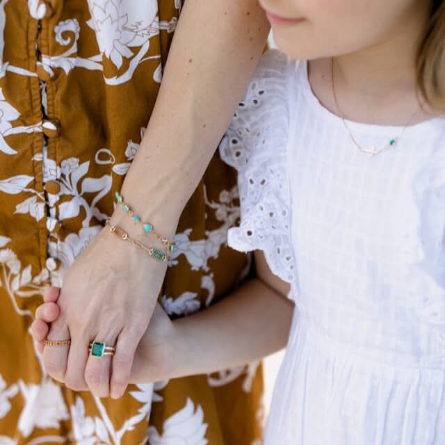 Woman adorned with assorted Haverhill 14k gold rings, including a Warren Vertical Ring, showcasing one 10 x 8 mm emerald cut, bezel set Emerald.