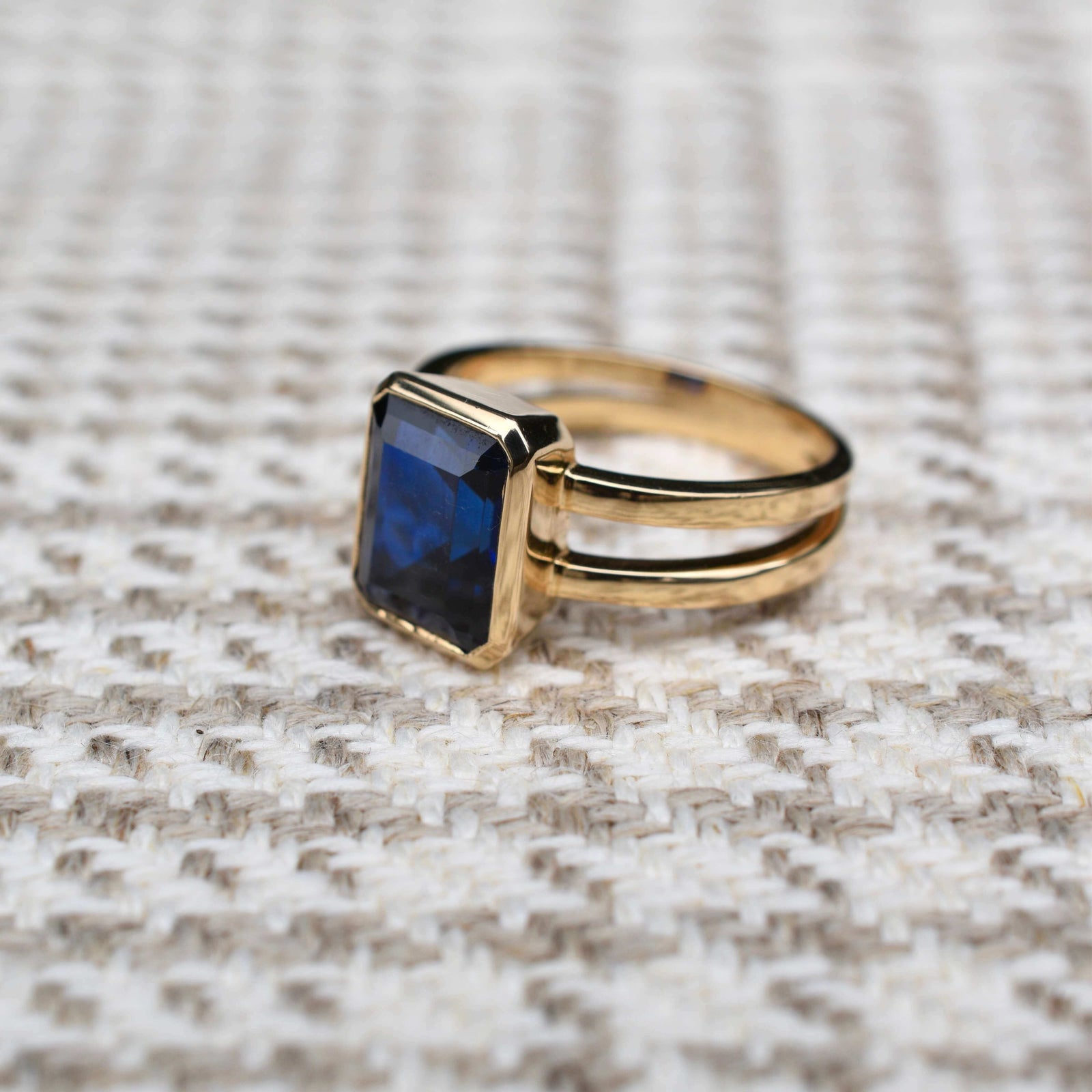 Warren ring in 14k yellow gold featuring one 10 x 8 mm emerald cut bezel set sapphire